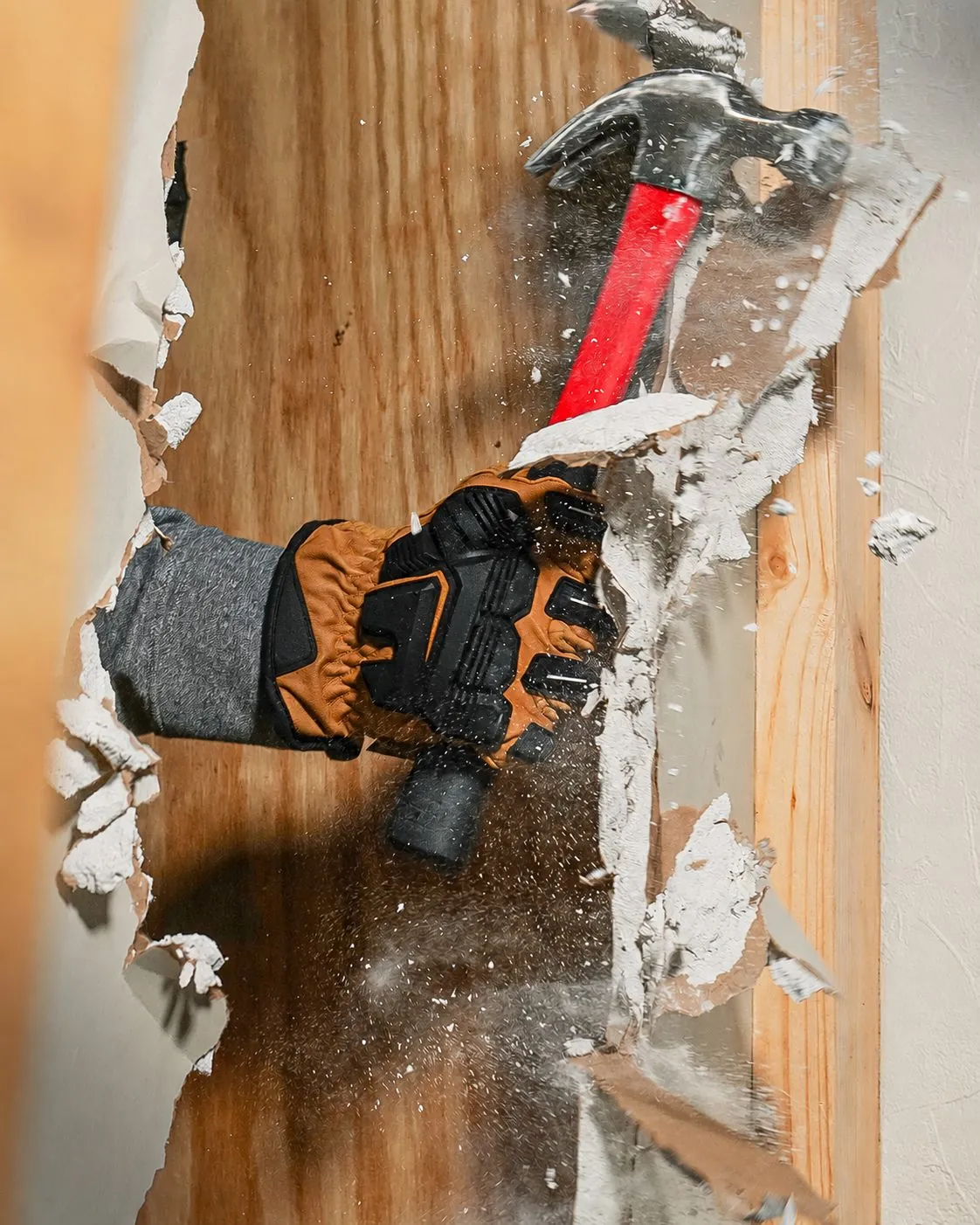 Main gantée cassant une cloison au marteau